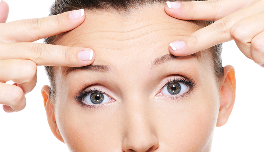 A woman using her fingers to stretch out the lines on her forehead. 